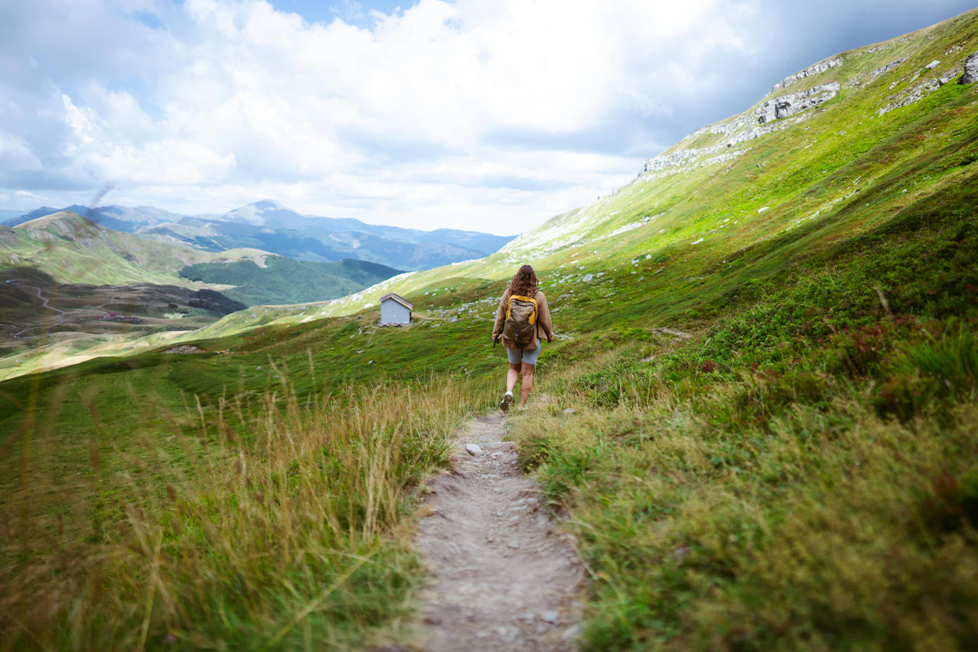 Woman walking along a mountain trail in outdoor clothing