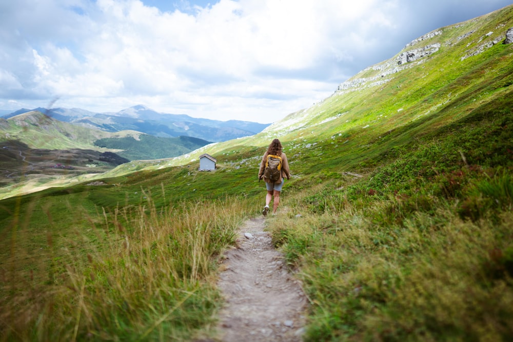 a woman walking up a trail in the mountains