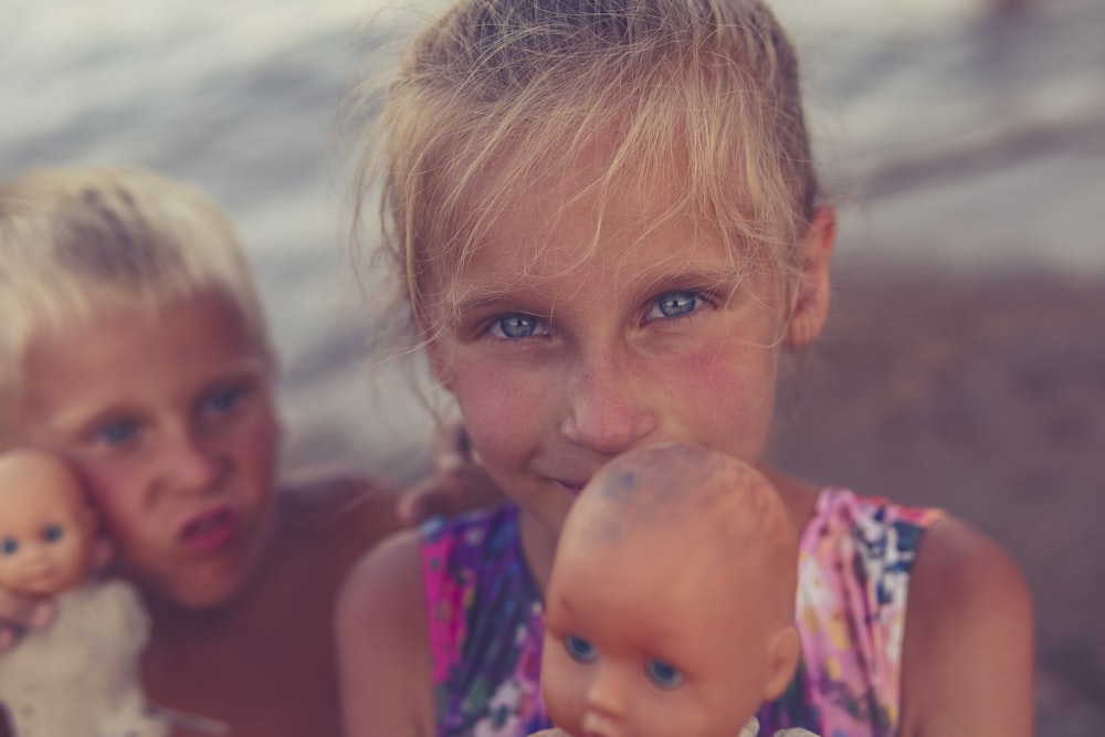 two little girls are playing with dolls on the beach