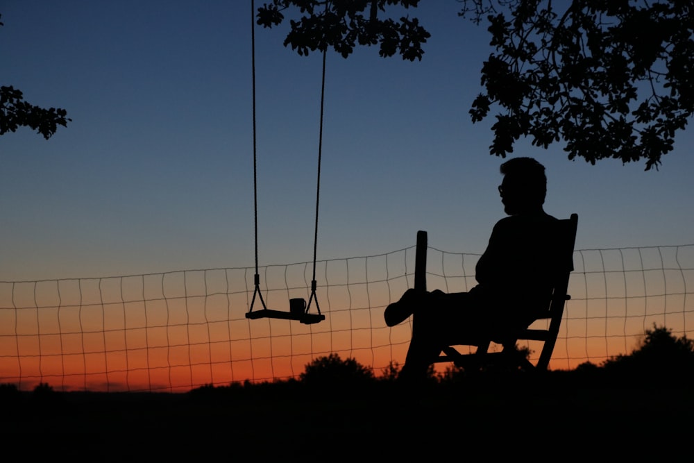 a man sitting in a chair next to a swing