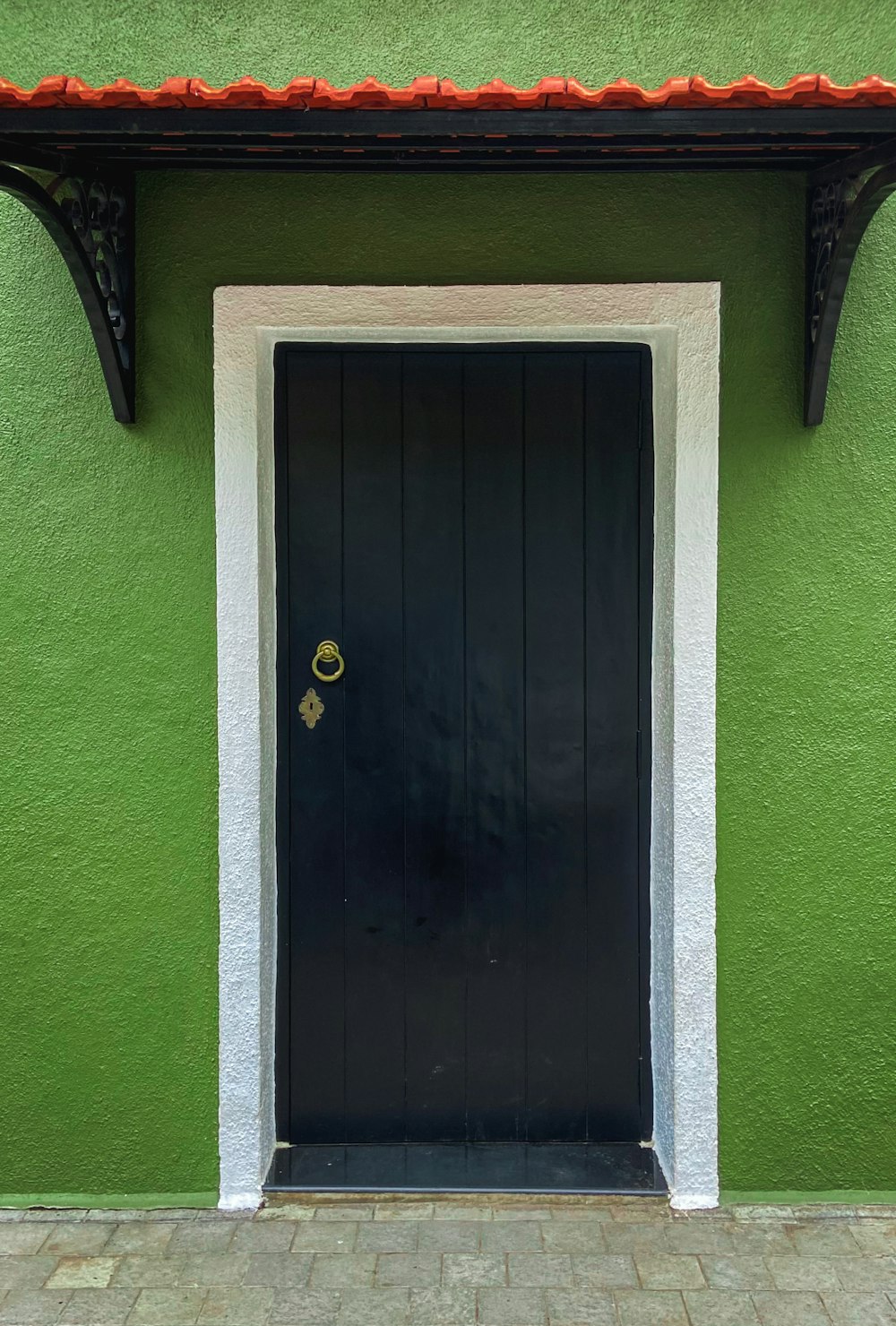 a green building with a black door and white trim