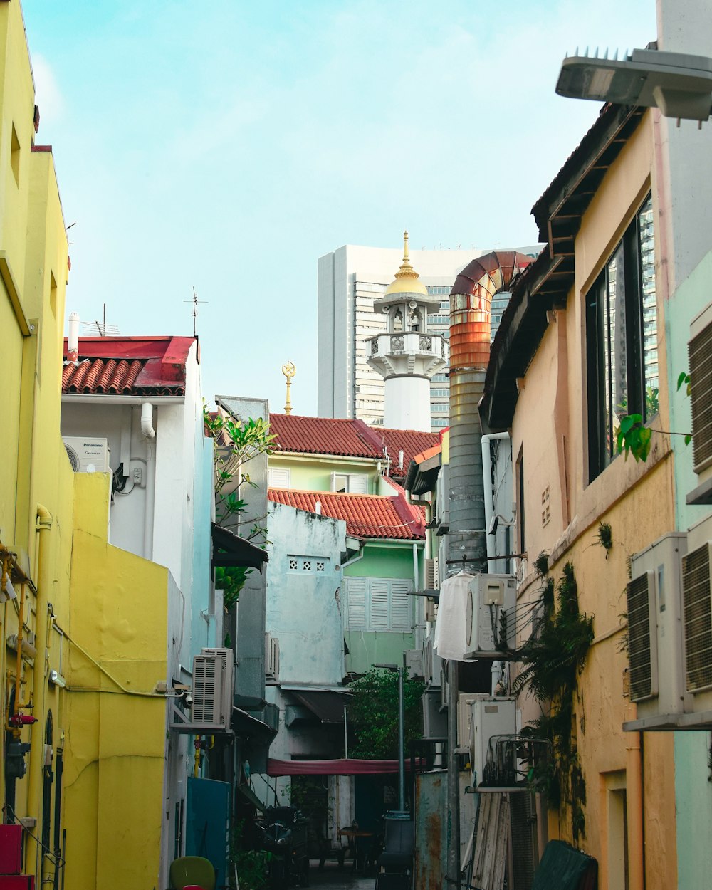 a narrow alley way with buildings and a clock tower in the background