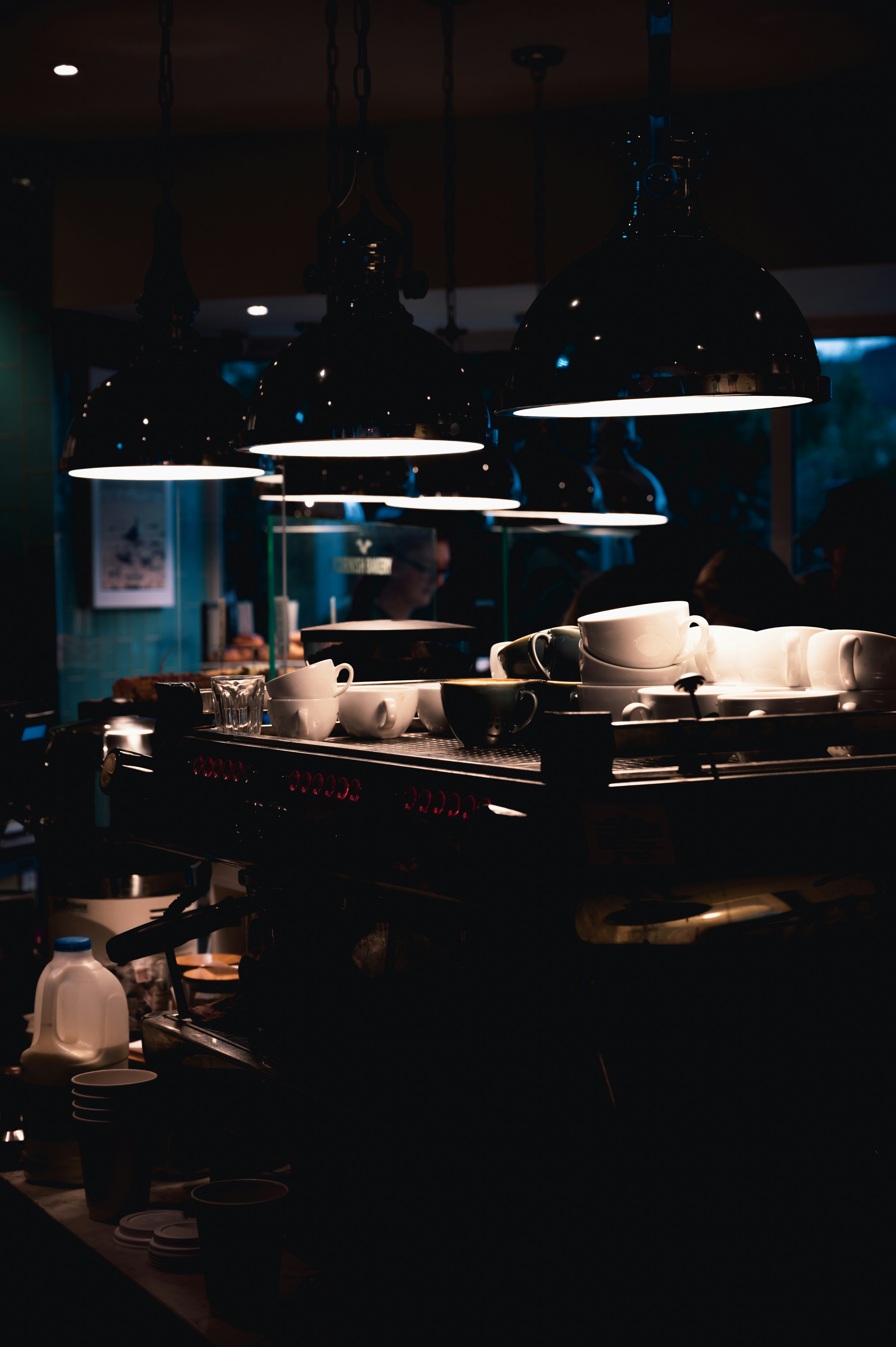 Artisan coffee being poured in a dark café, moody low-key lighting, deep shadows, atmospheric steam, minimal background