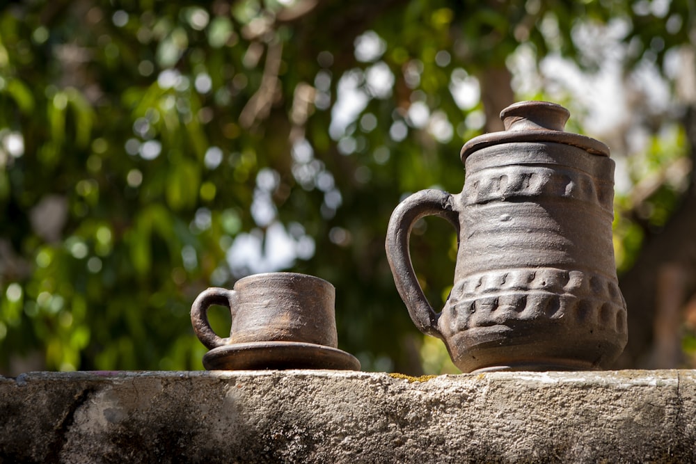 a couple of cups sitting on top of a stone wall