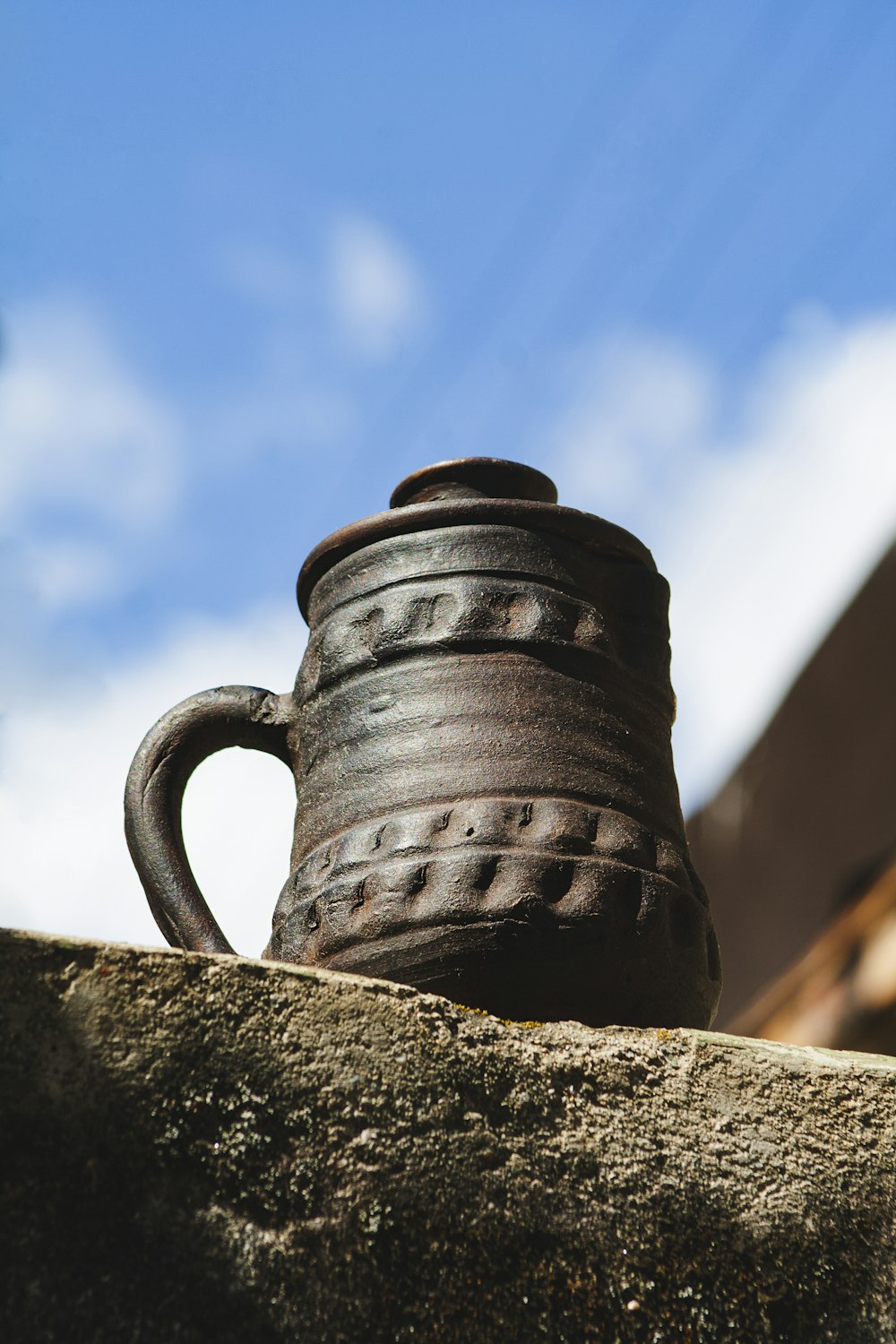 une tasse brune posée au sommet d’un mur de pierre