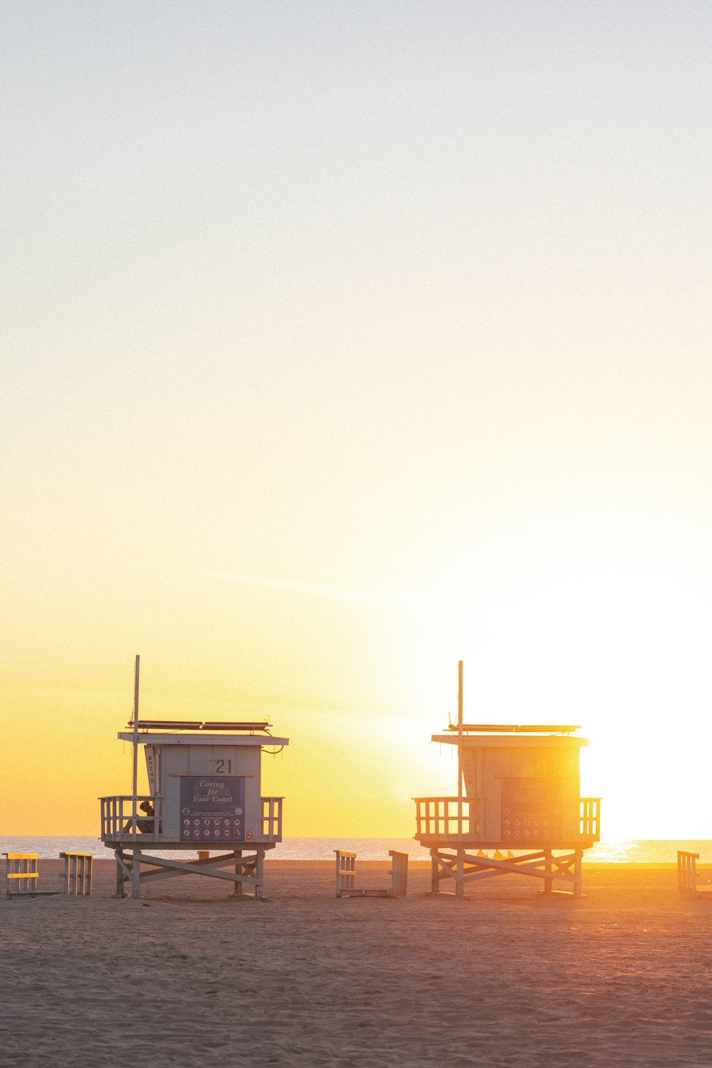 a couple of lifeguard huts sitting on top of a sandy beach