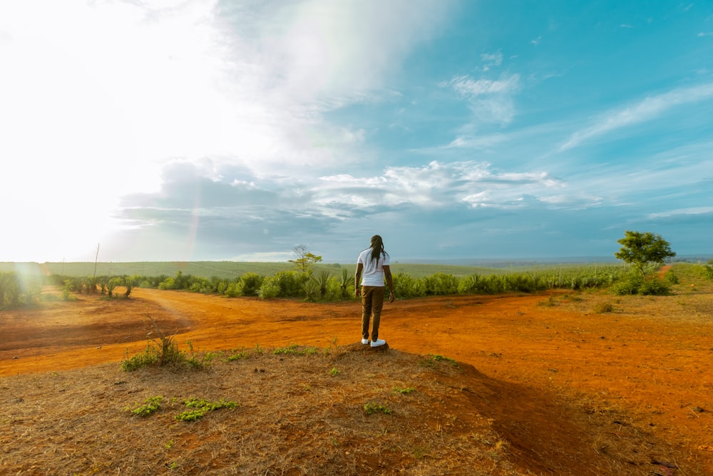 a woman standing on top of a dirt field