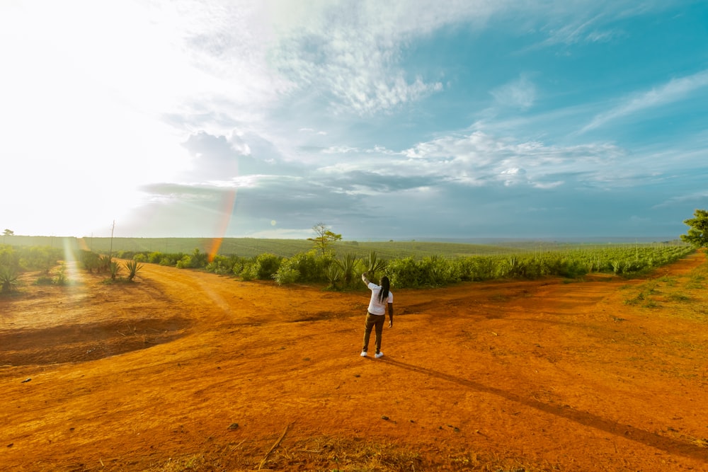 a person standing in the middle of a dirt road