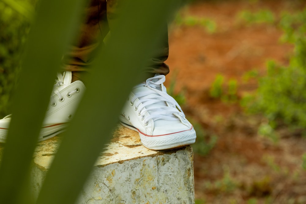 a person standing on a rock with white shoes