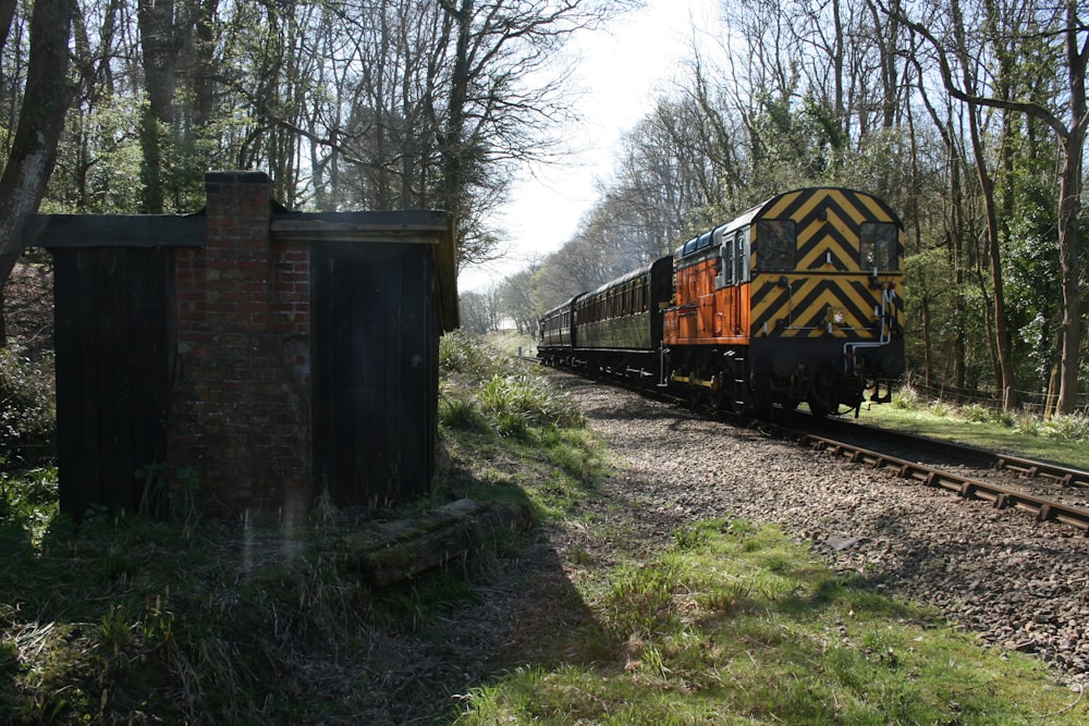 un train descendant les voies ferrées à côté d’une forêt