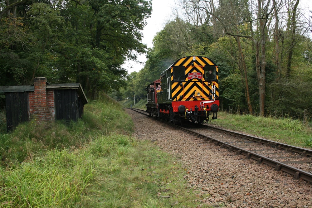 un train descendant les voies ferrées à côté d’une forêt