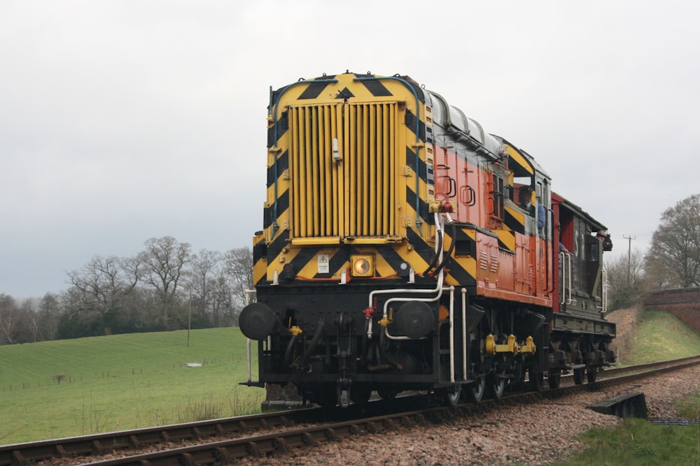 a train traveling down train tracks next to a lush green field