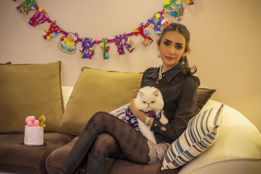 a woman sitting on a couch holding a cat