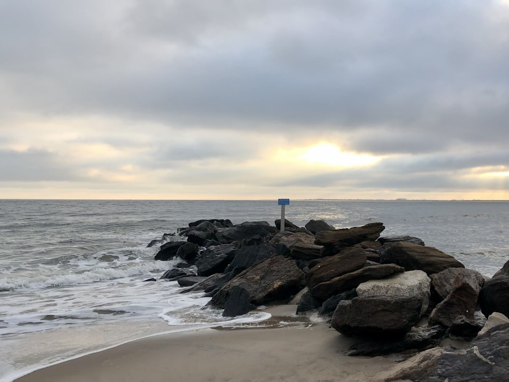 a beach with rocks and water under a cloudy sky