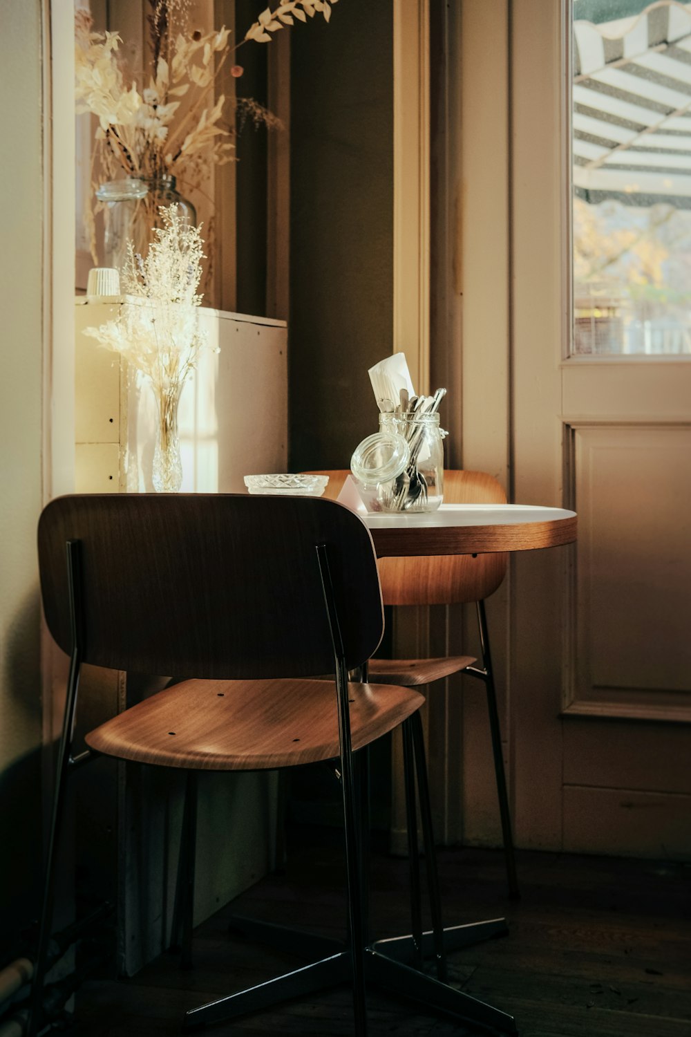 a wooden chair sitting next to a table with a vase on top of it