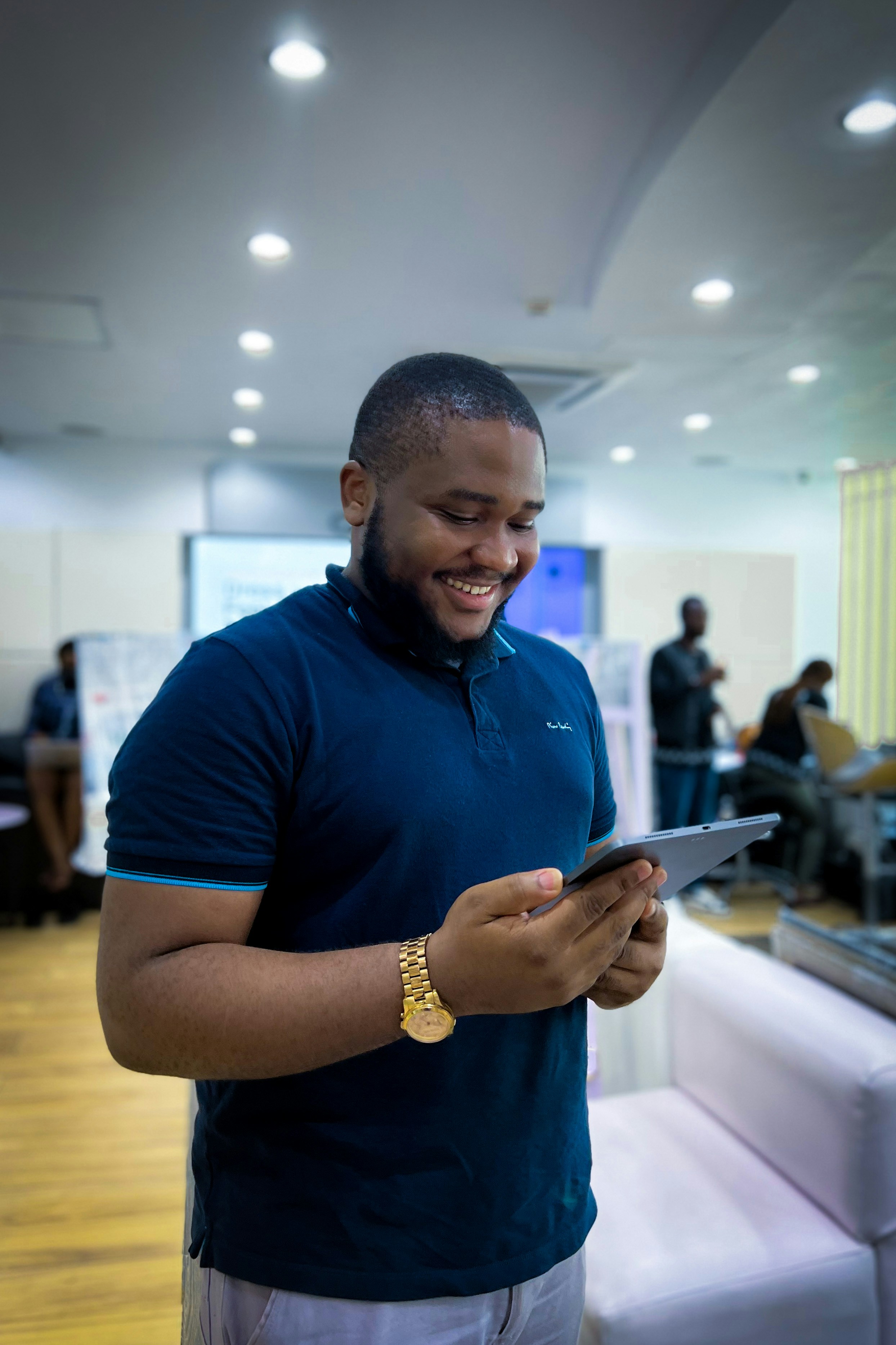 A man is happy looking at his iPad and holding it as well.