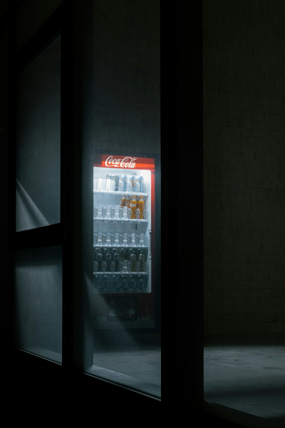 a lighted coca - cola cooler in a dark room