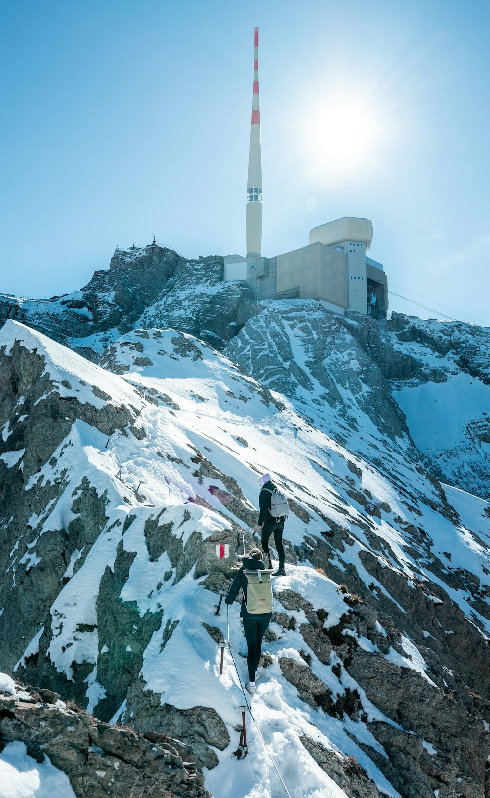 a couple of people walking up a snow covered mountain