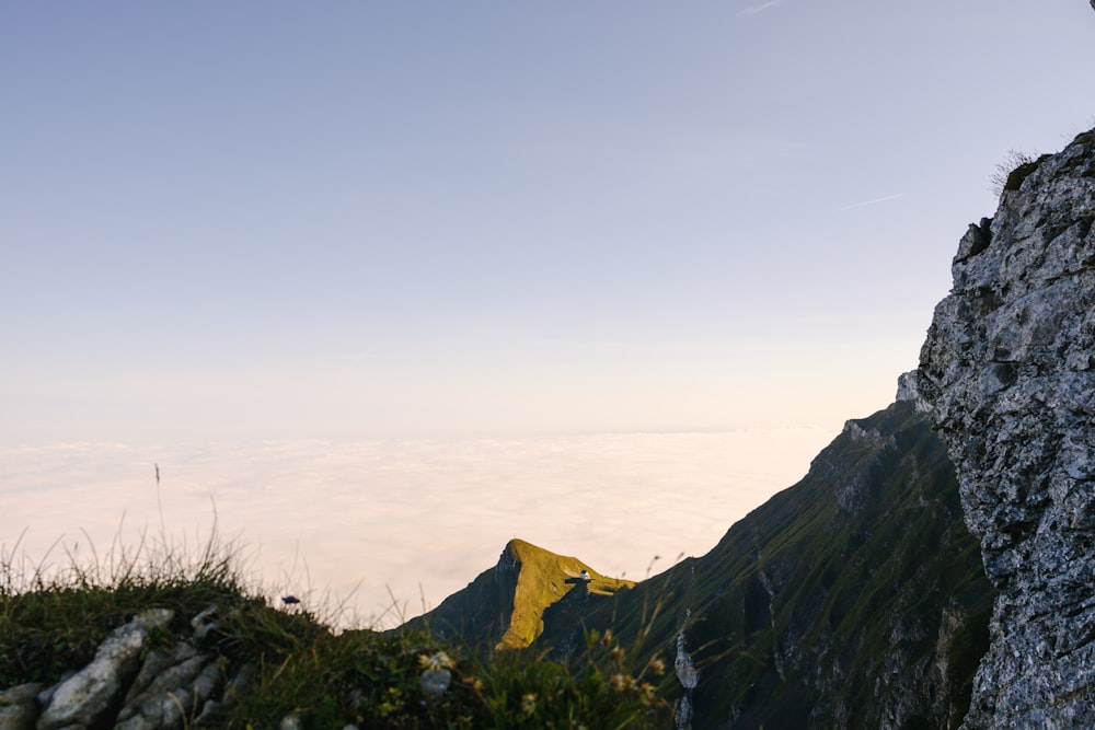 a man standing on top of a mountain next to a yellow flag