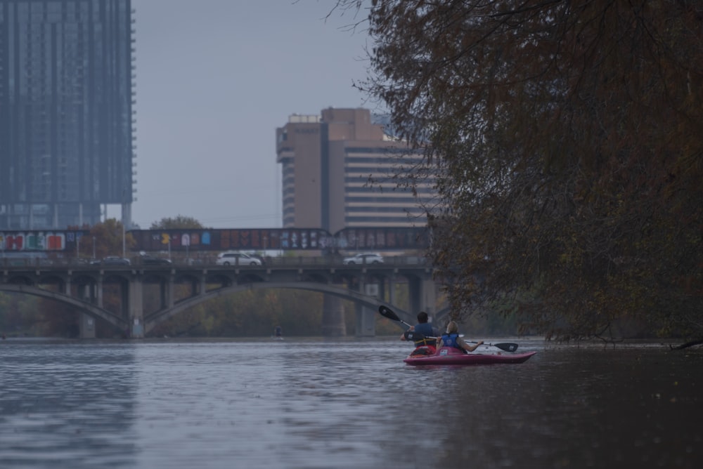 a person in a kayak on a river with a bridge in the background