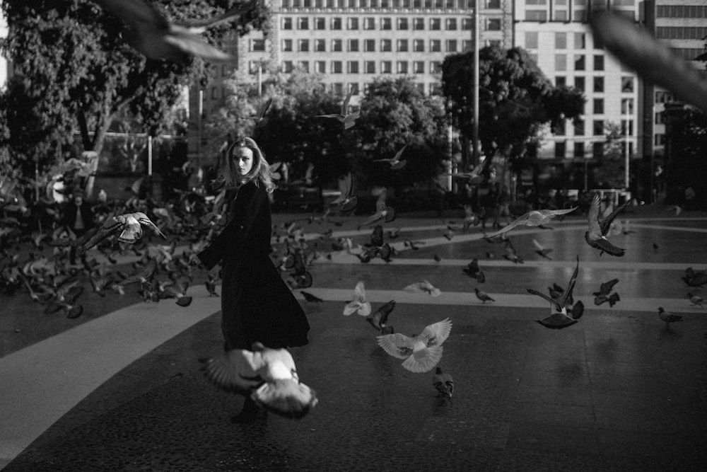 a woman walking down a street surrounded by birds