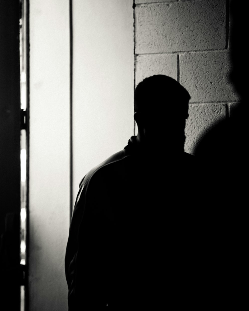 a man standing in front of a brick wall