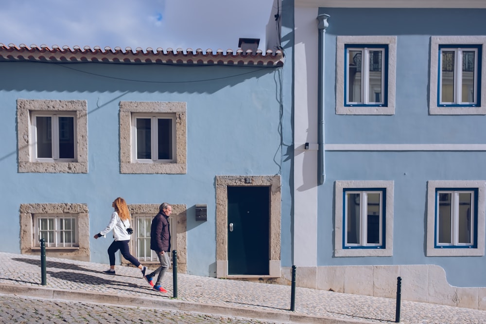Una pareja de mujeres caminando por una calle junto a un edificio azul