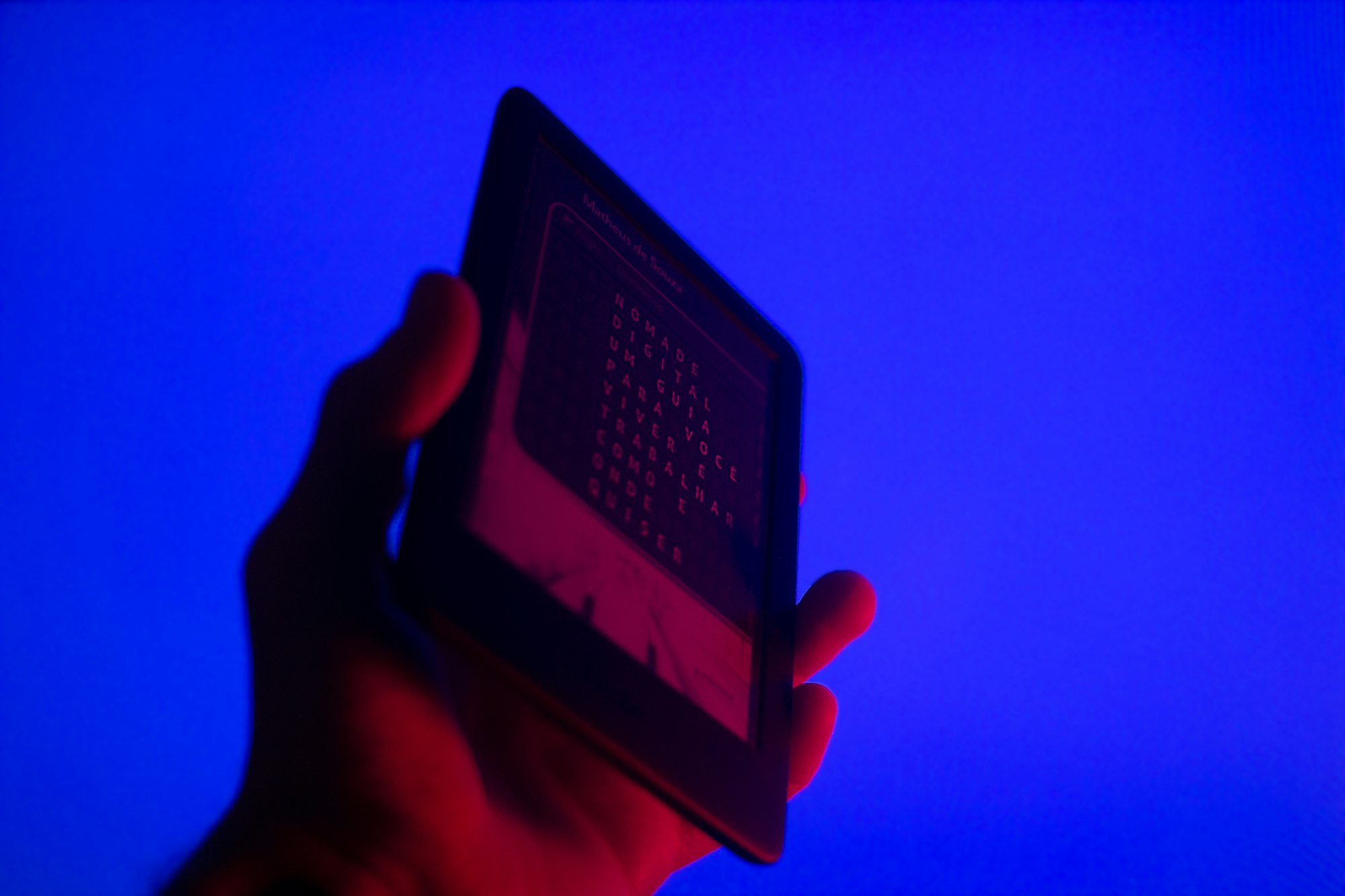 a hand holding a cell phone in front of a blue background