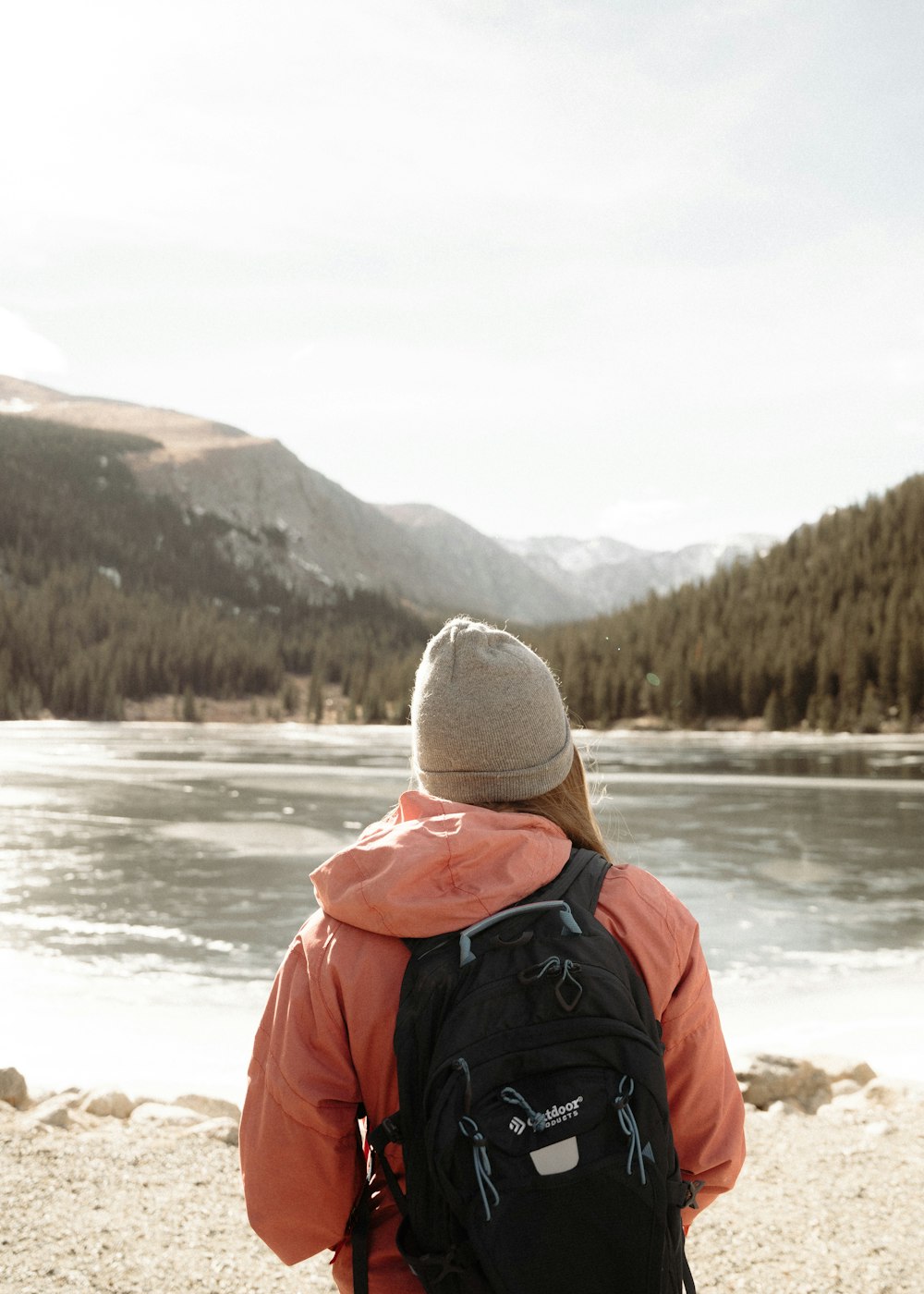 a person with a backpack looking at a lake