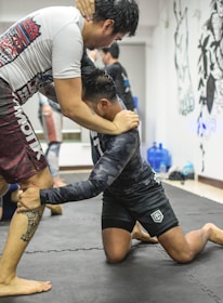 Two athletes engaged in a grappling match on a mat.