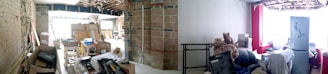 A partially renovated interior space with exposed bricks and beams. The area is cluttered with construction materials, cardboard boxes, and various tools. On the right, there is a small sitting area with a refrigerator, a stuffed animal, and other household items.