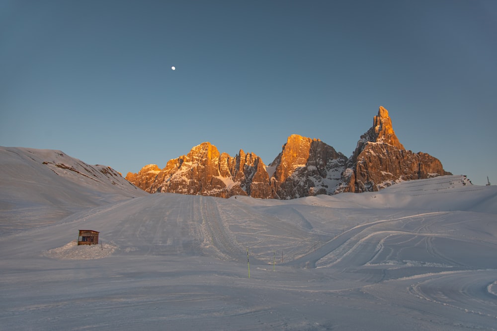 a snow covered mountain with a small cabin in the foreground