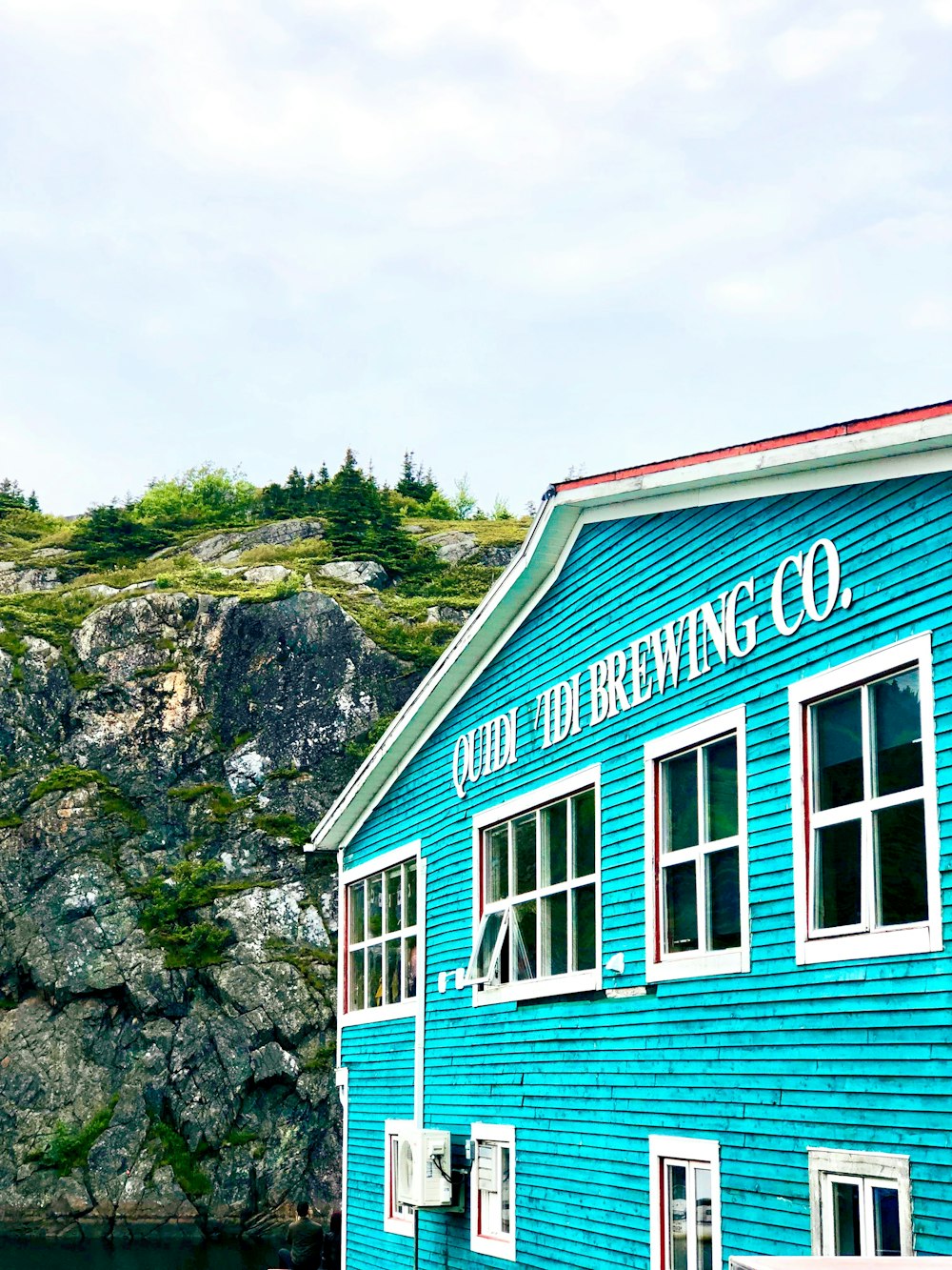 a blue building with a red roof next to a body of water