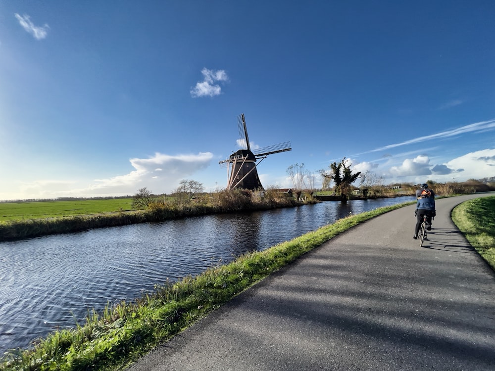 a man riding a bike down a road next to a river