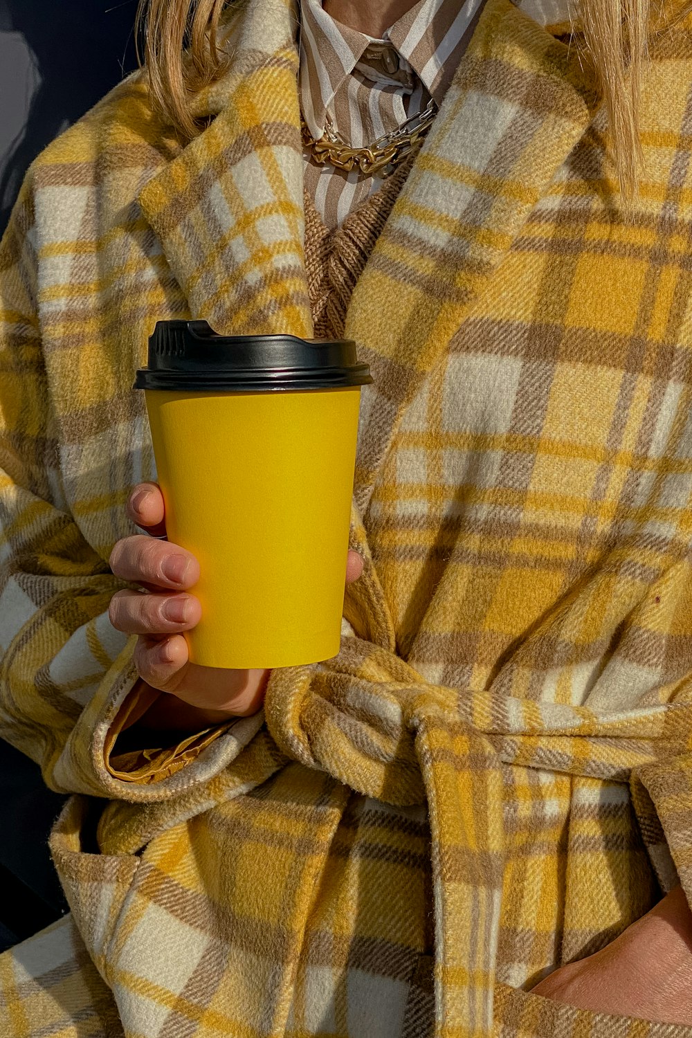 a woman holding a yellow cup of coffee