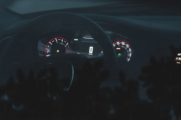 Dashboard illuminated in neon red lighting during a night drive on an urban highway