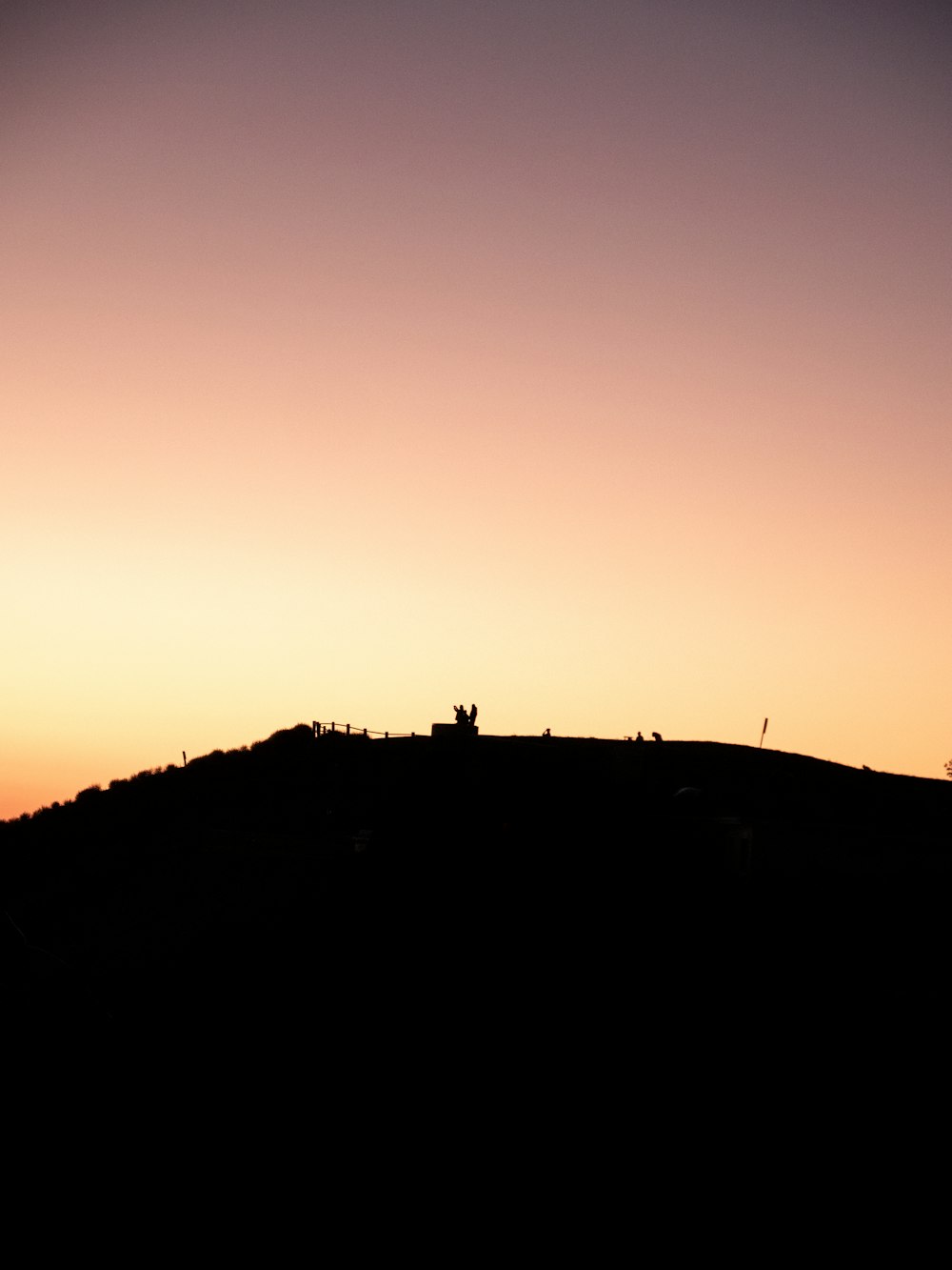 a silhouette of a hill with a person standing on top of it