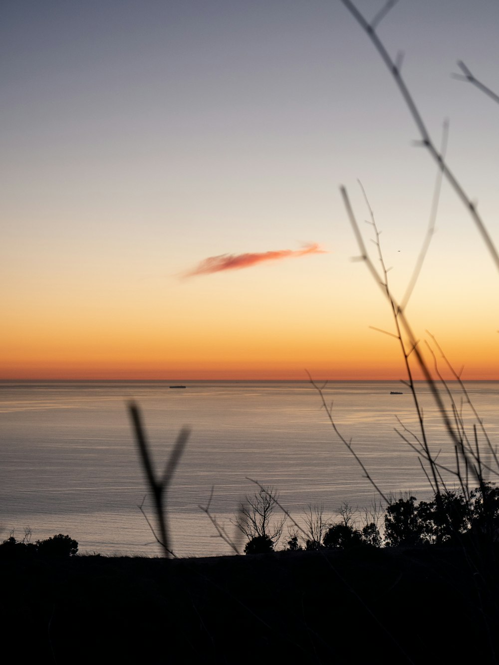 a view of the ocean at sunset from a hill