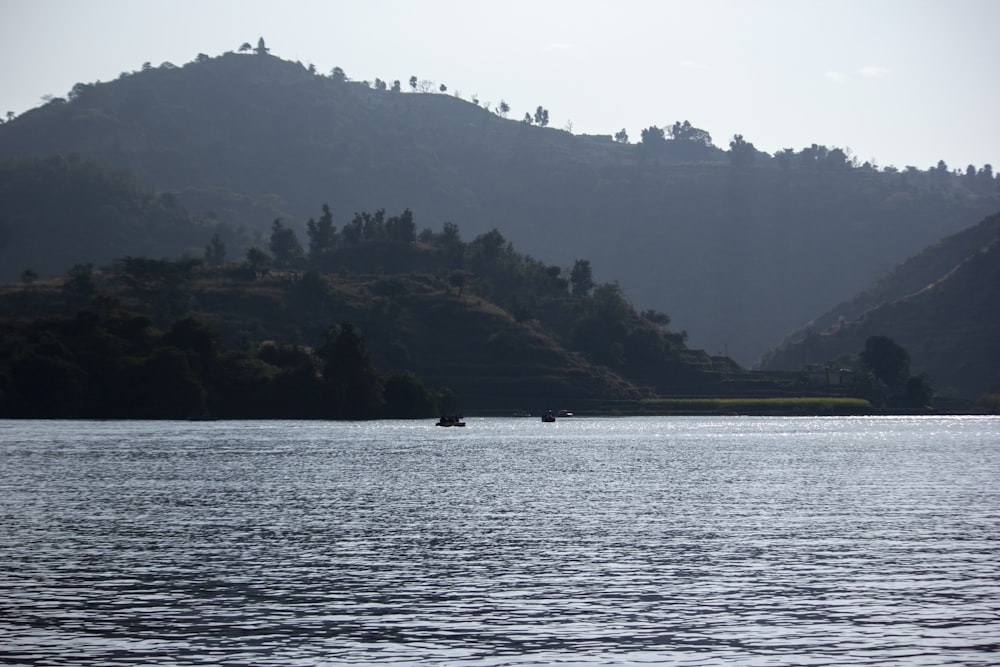 a body of water with a hill in the background