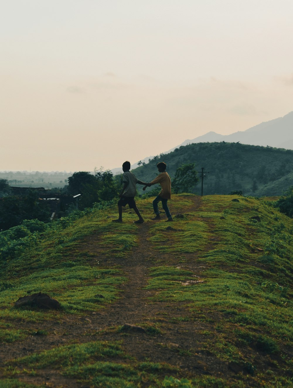 a couple of men standing on top of a lush green hillside