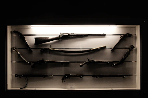 Display cases filled with various firearms neatly arranged under warm lighting.