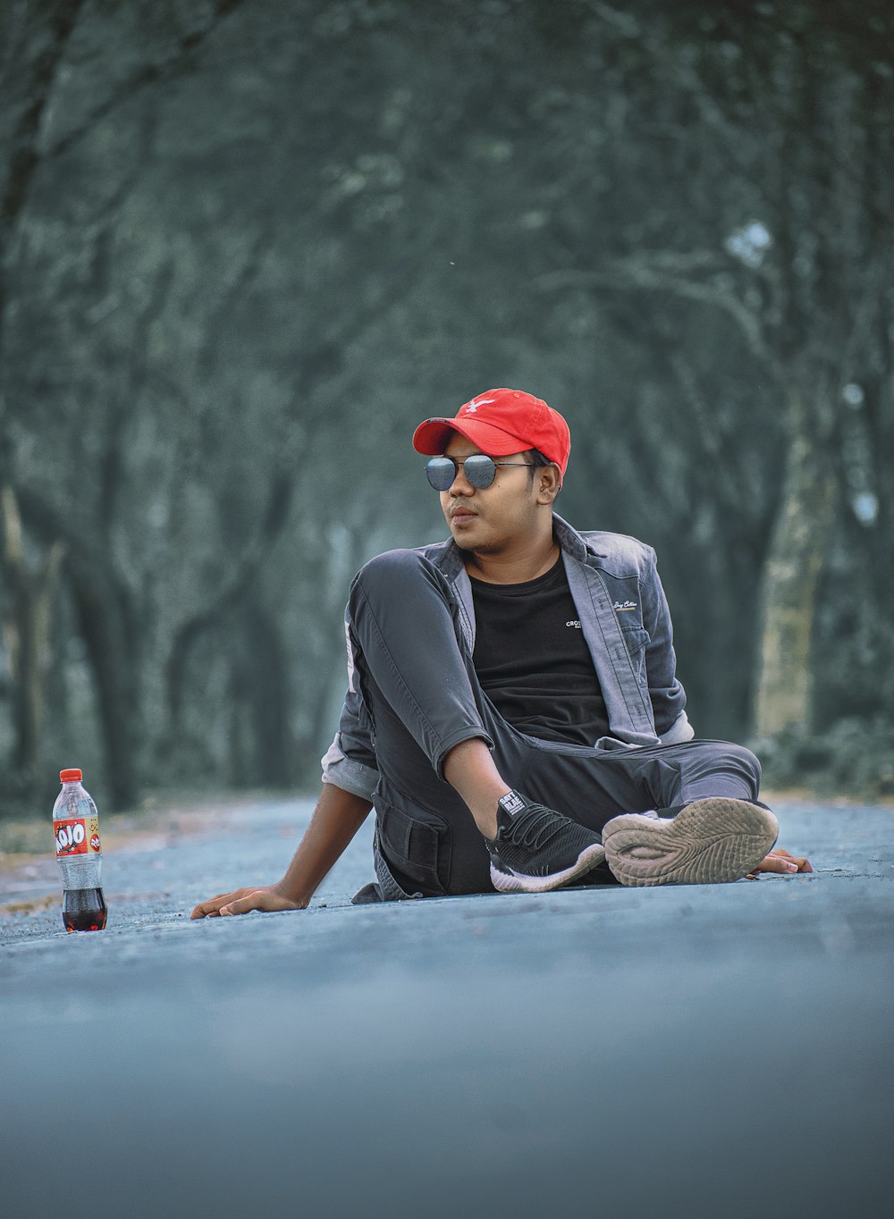 a man sitting on the ground next to a bottle
