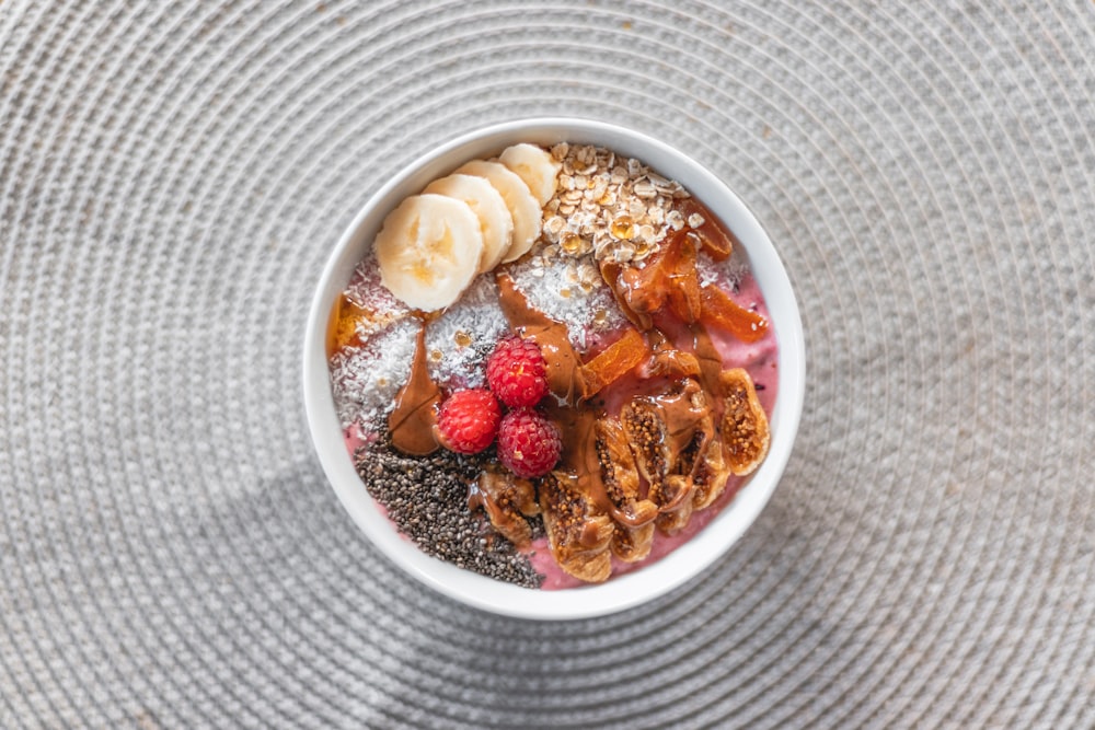 a bowl of food with bananas, raspberries, and powdered sugar