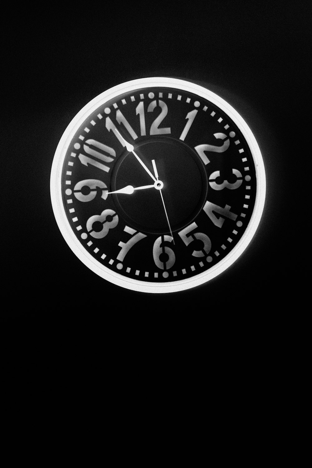 a black and white clock on a black wall