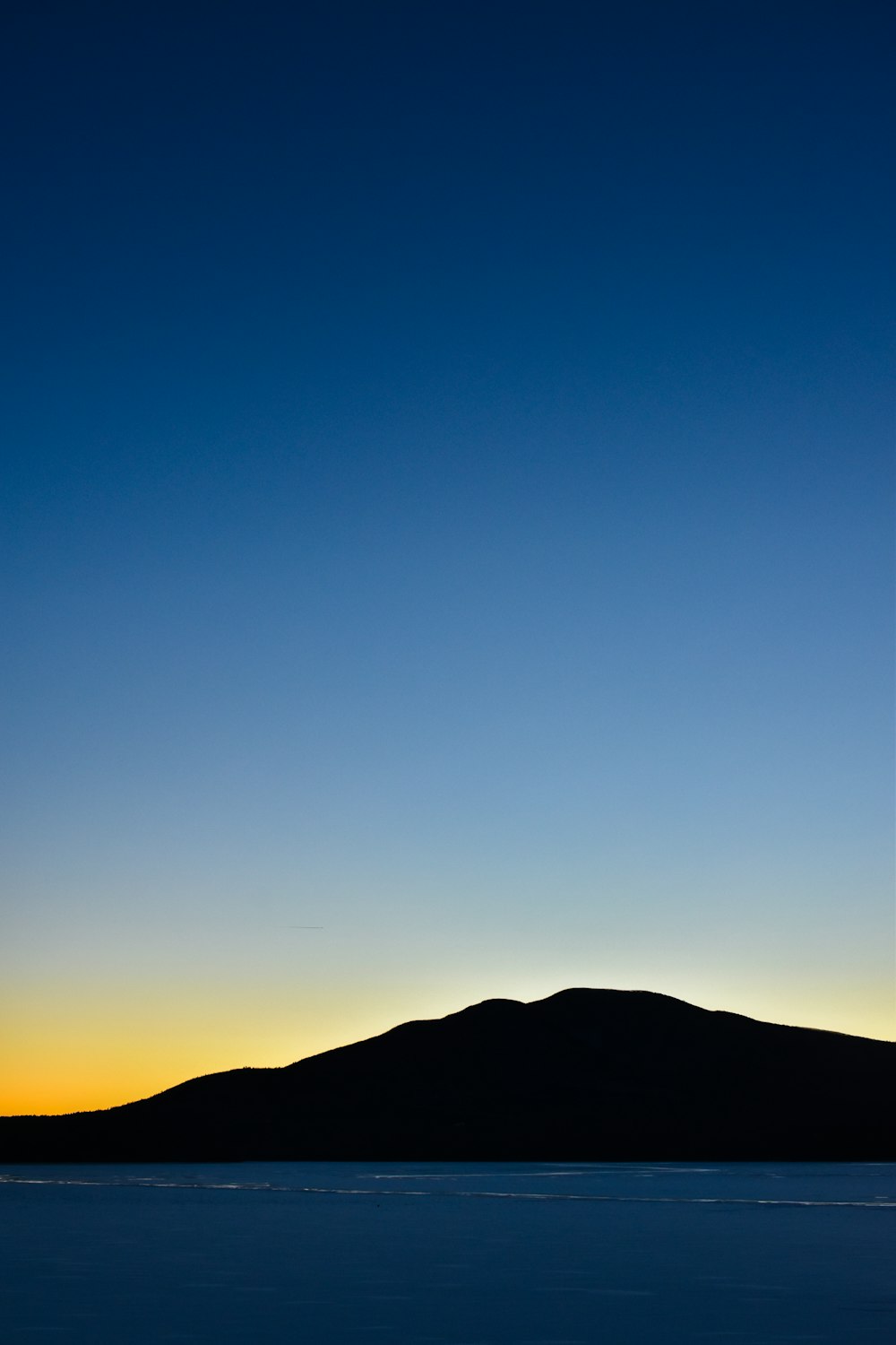 ein großes Gewässer mit einem Berg im Hintergrund