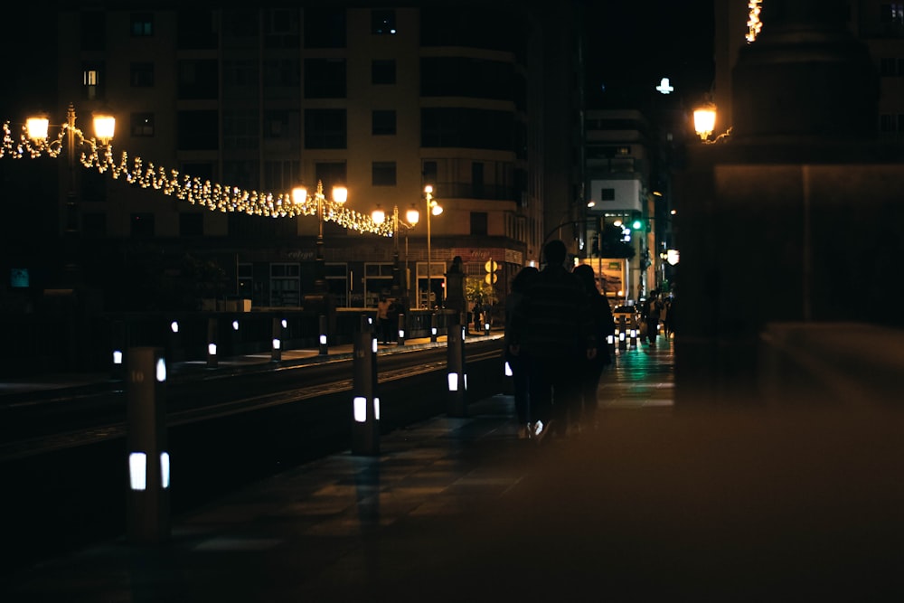 a couple of people walking down a street at night