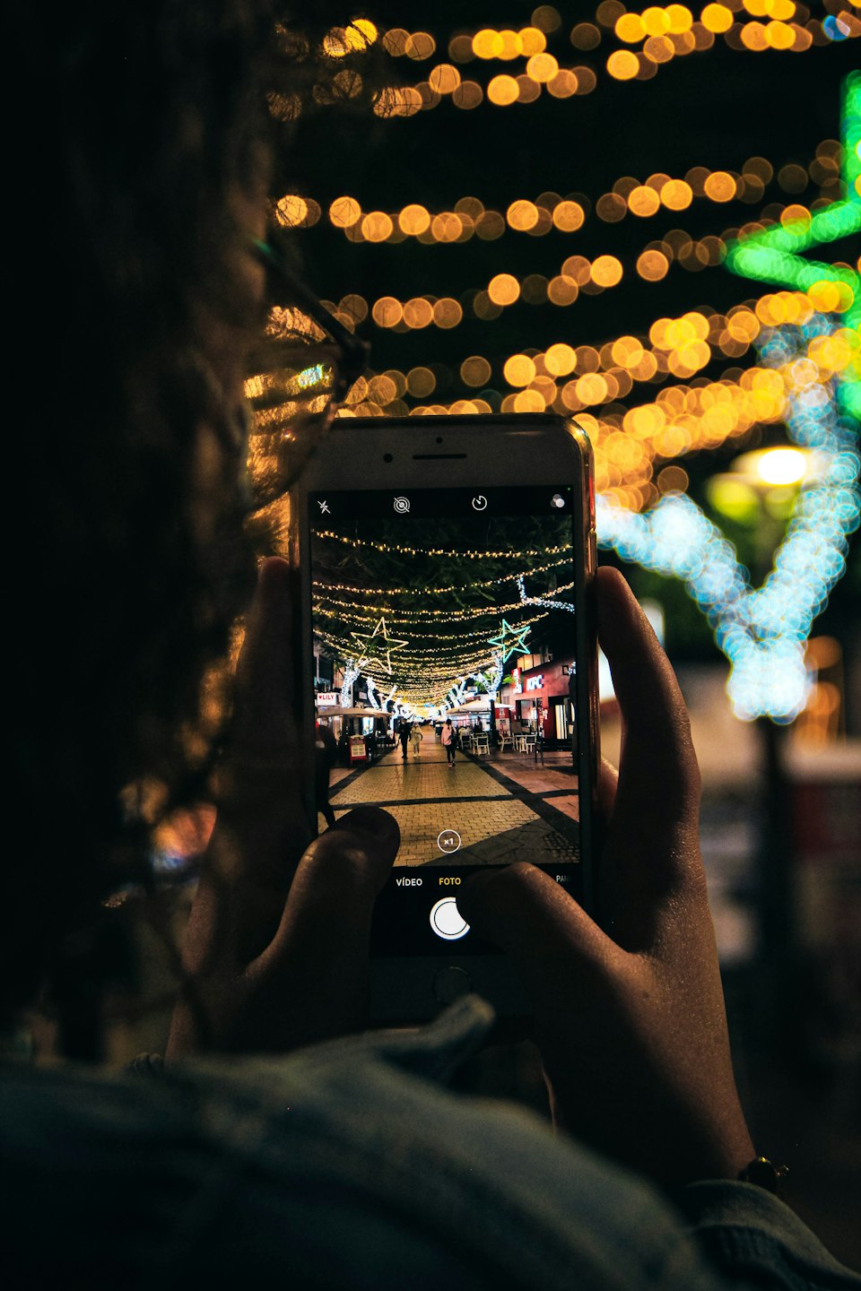 A nighttime street scene in Santa Cruz de Tenerife with illuminated storefronts