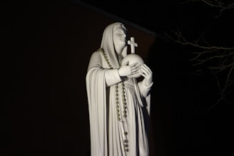 A serene statue of Saint Jude Thaddaeus holding a flame and a medallion, symbolizing hope and faith.
