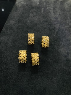 Arrangement of various gold rings with subtle textures and delicate shapes on a smooth ivory surface.