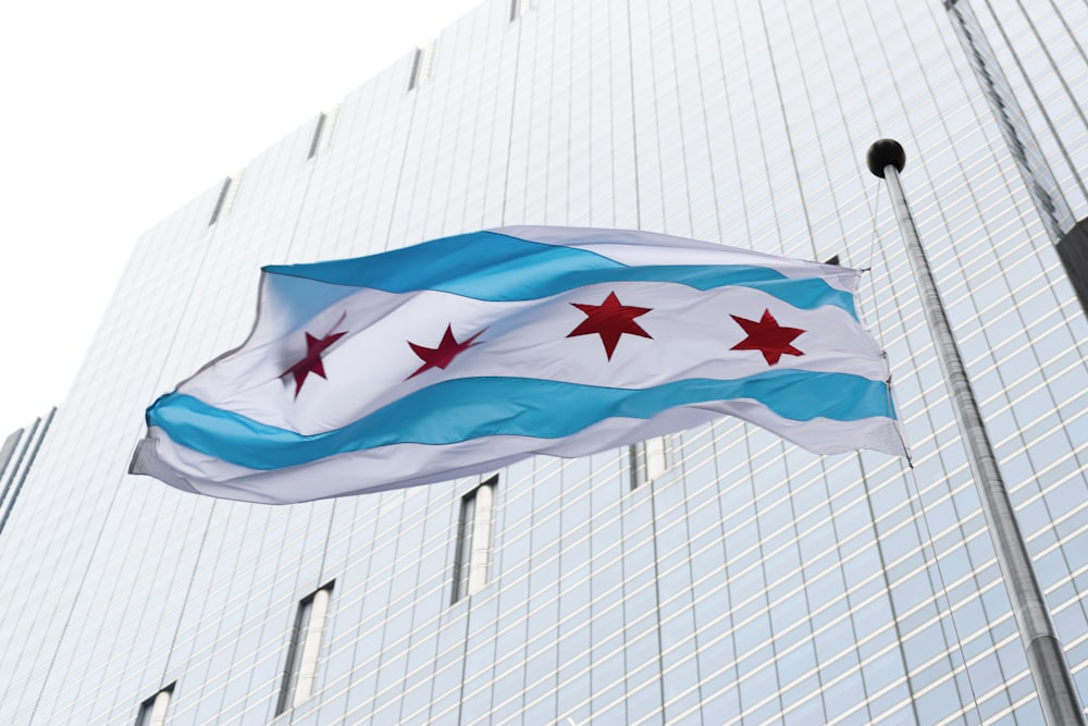 a flag flying in front of a tall building